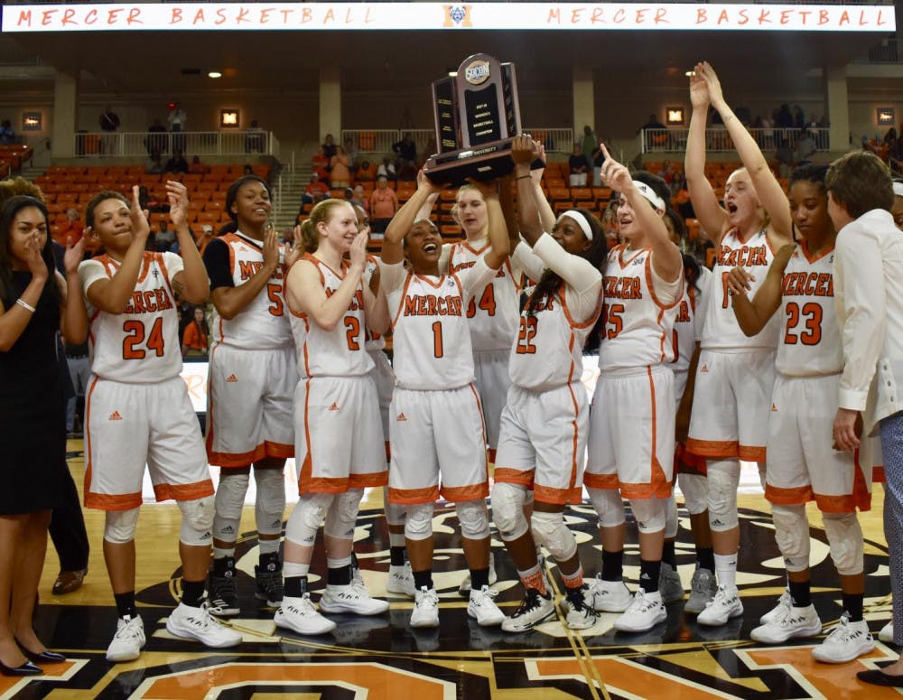 The Women's basketball team holds their regular season title trophy high for Hawkins Arena.