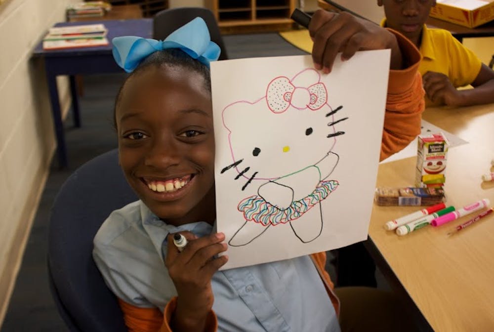 A girl who attends the afterschool arts program at Tindall Heights shows off one of her creations.