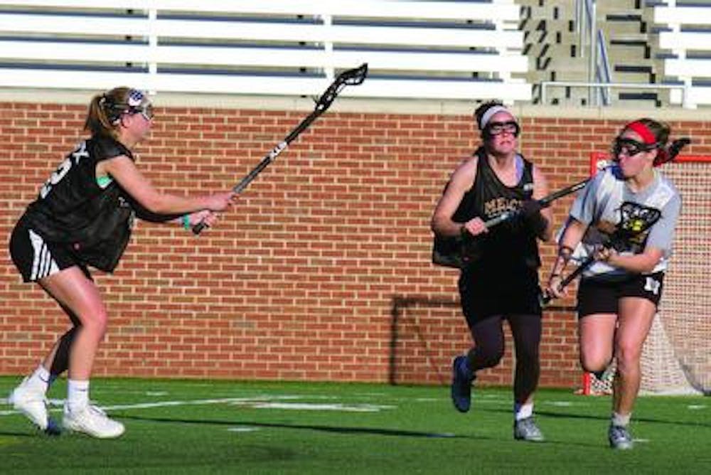 Midfielder Kelly Hagerty runs the ball at practice, defended by midfielders Anna Schneeberger (left) and Lindsey Zeltwanger.