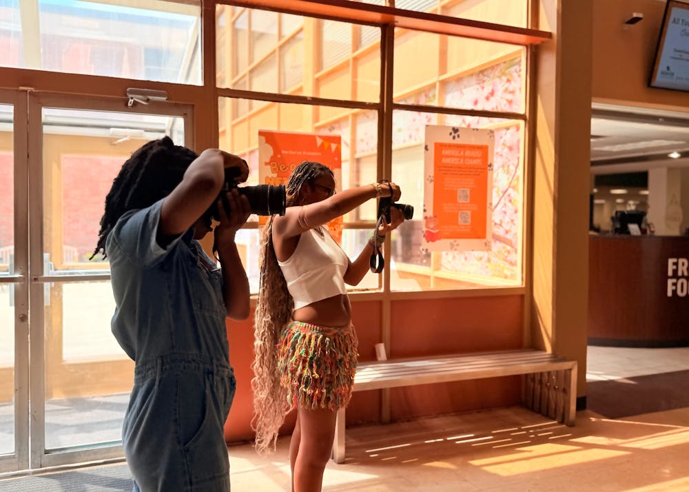 Jassmyn Nesmith '26 (left) and Taylor Goodly '26 (right) collaborate to collect candids of students as they pass through the Connell Student Center lobby. 