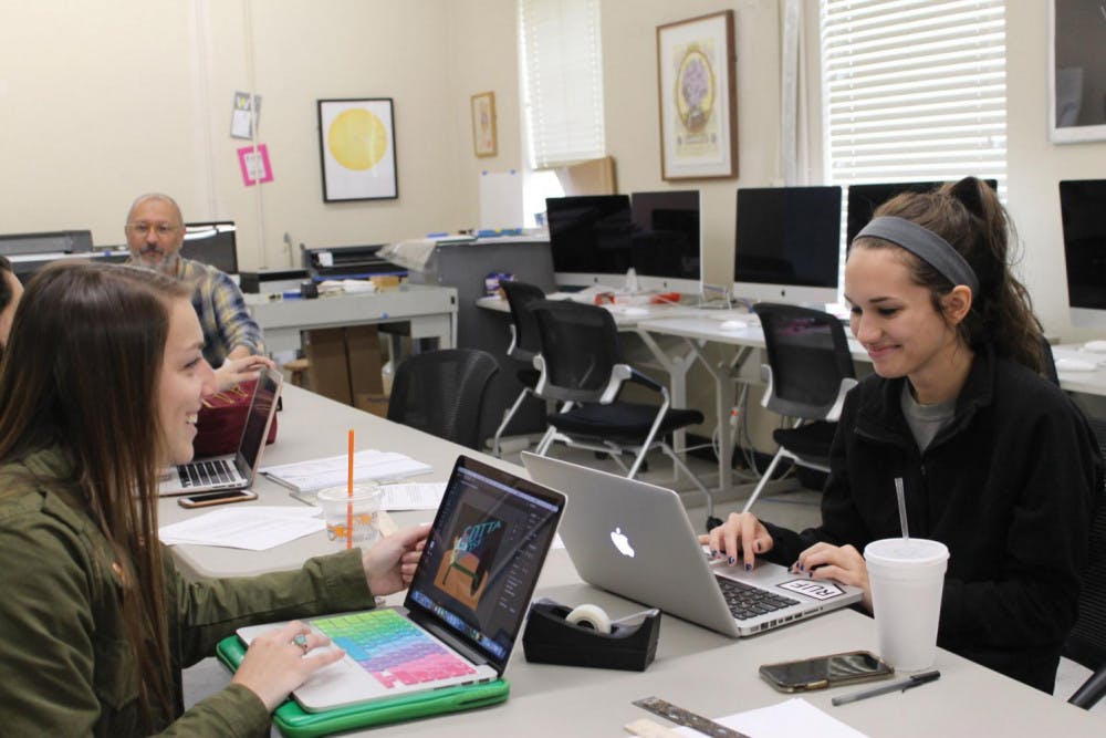 Graphic design students Megan Gates and Bethany Alexander prepare for the 2018 Senior Arts Show. 