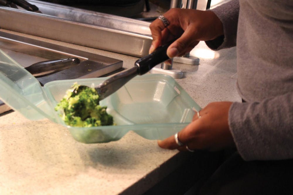 A student places food into a container at the Fresh Food Company.