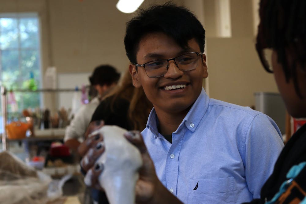 Universidad Tecnológica de Izúcar de Matamoros student Román Osorno smiles learning about a Mercer student's final project for the ceramics course.