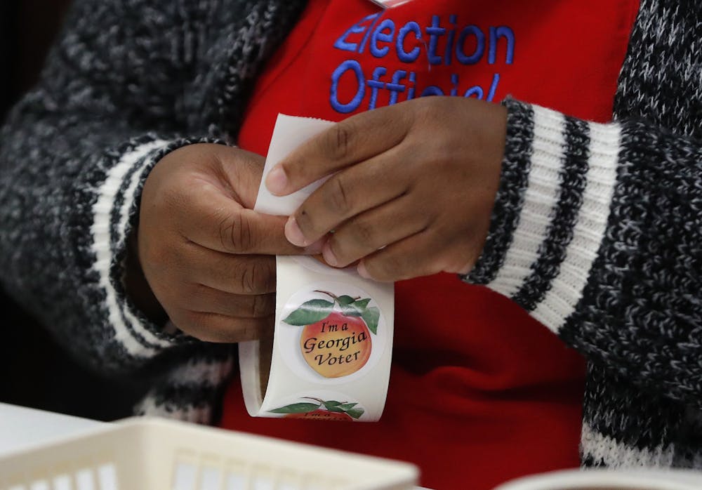 A poll worker peels stickers off a roll as Georgia voters casts ballots Tuesday, Nov. 6, 2018, in Winterville, Ga. (AP Photo/John Bazemore)
