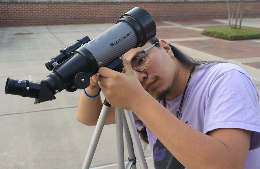 <p>Manuel Flores toggles with a telescope on the University Center patio while getting ready to look at the night sky later that day.</p><p><br/></p>