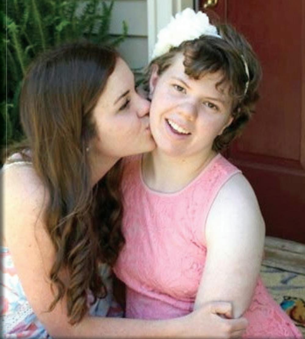 Katie (left) kisses her sister sister, Maggie on the cheek, Maggie suffers from an intractable seizure disorder.