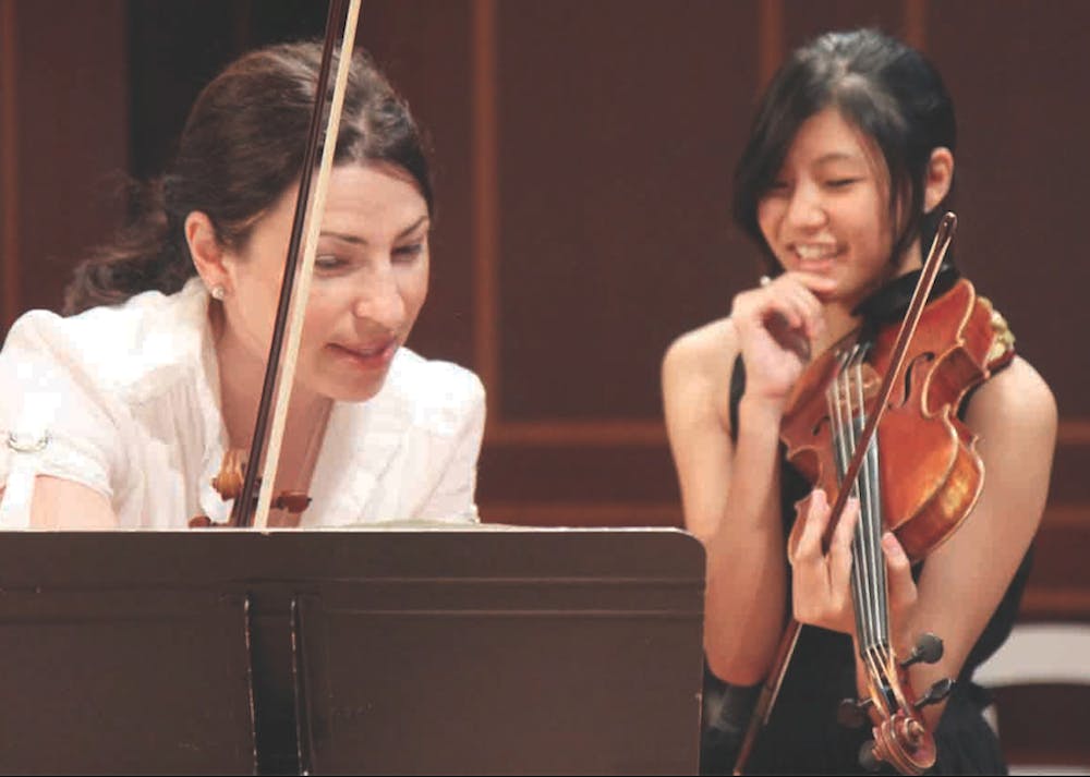 Amy Schwartz Moretti, a violinist in the Outstanding Octets concer, works with previous student Jecoliah Wang.