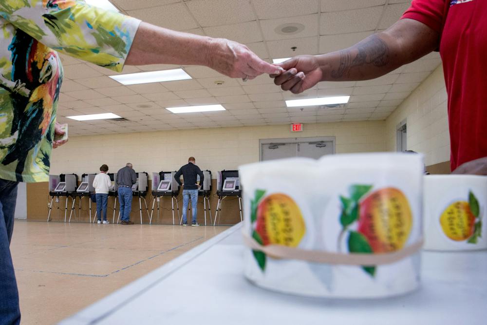 "I'm a Georgia Voter" stickers with peaches are handed out to residents as they vote during Georgia's primary election at their polling station at South Lowndes Recreation Complex in Lake Park, Ga., Tuesday, March 1, 2016. (AP Photo/Andrew Harnik)