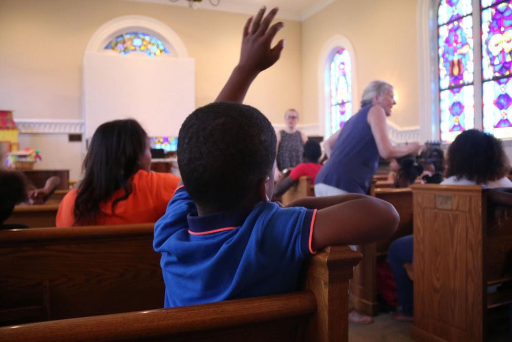 A Freedom School student raises his hand to ask a question during morning warm ups. The fifty students who attend Freedom School meet at St. Paul's Episcopal Church every morning for Harambe, a Swahili word that means "coming together."