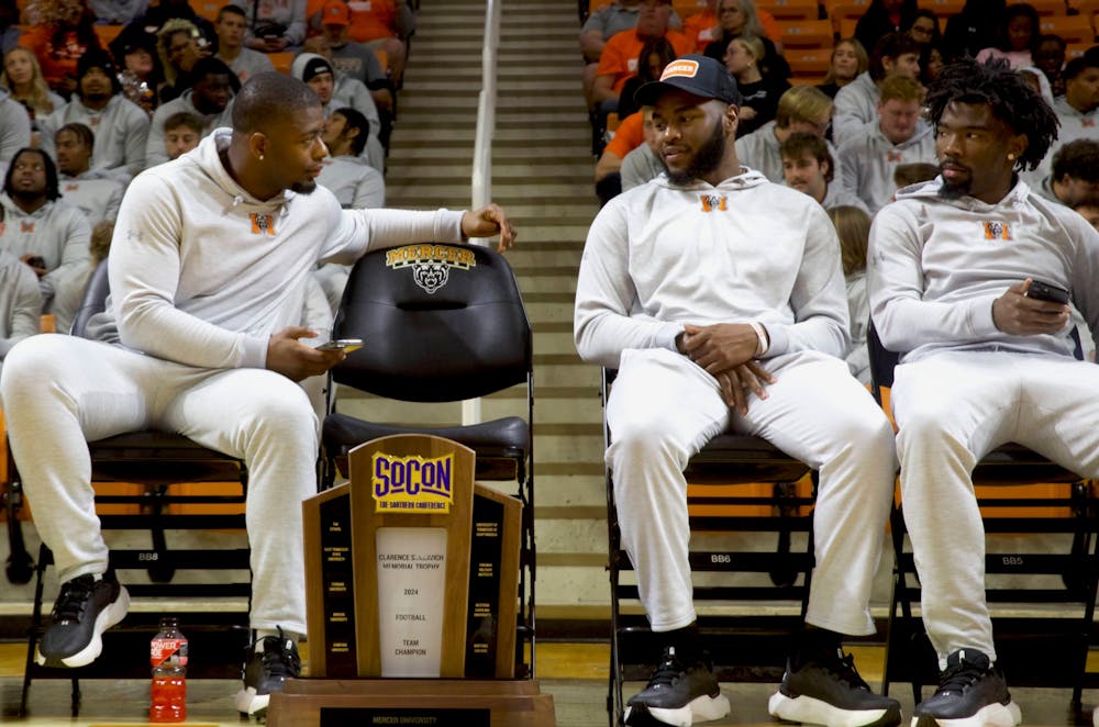 From left, Isaac Dowling Jr. '25, Ken Standley '25 and TJ Moore '25 sit in Hawkins Arena on Sunday to learn Mercer's seeding in the 2024 FCS Playoffs.