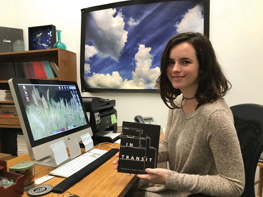 Editor-in-Chief Chelsea Carr sits with last year's Dulcimer magazine titled "In Transit."