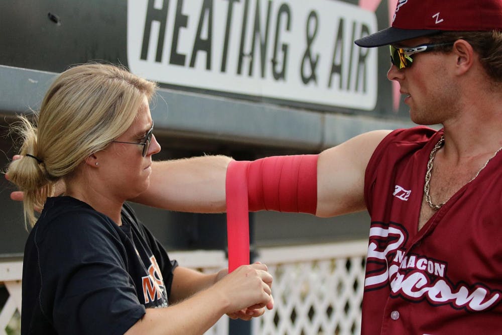 After pitching, Isabella Haswell uses blood flow restriction therapy to help with the muscle endurance for one of the players.