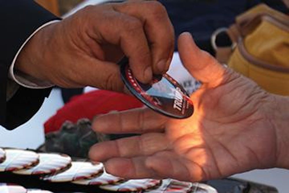 Tim Engelskirchen of Charlotte, North Carolina sells buttons to the people at the 2015 Donald Trump campaign rally in Macon, Georgia. Engelskirchen yells, "Make America great again buttons, hats and t-shirts," as people walk by to enter The Macon Centreplex Coliseum and Convention Center.