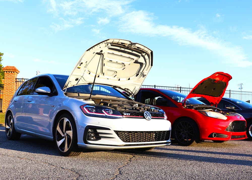 <p>Gabe Diaz ‘27 and Andrew Cross ‘28 popped the hoods to their Volkwagen Golf GTI (left) and Ford Focus ST (right), to show off their engine bays.</p>