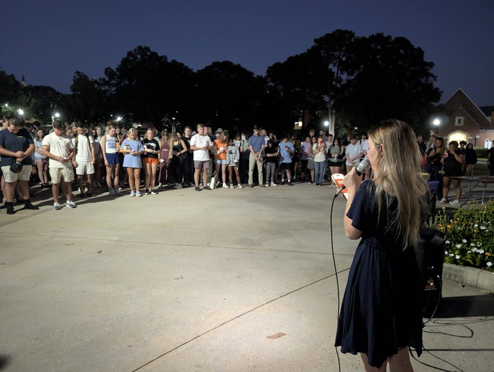 Emily Benelli '26 reads from her phone at Monday evening's event. Benelli said after the event that Charlie Kirk "went around on college campuses wanting young people to be heard."