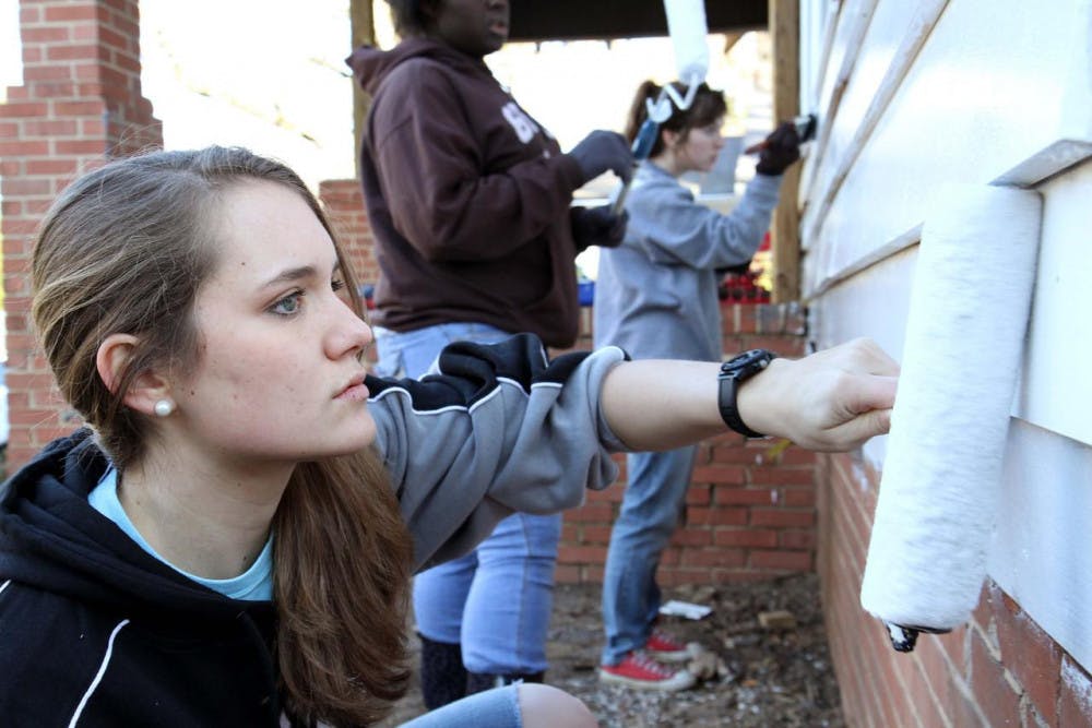 Janea Feeney helps paint the exterior of a house as part of the 2014 MLK Day of Service.