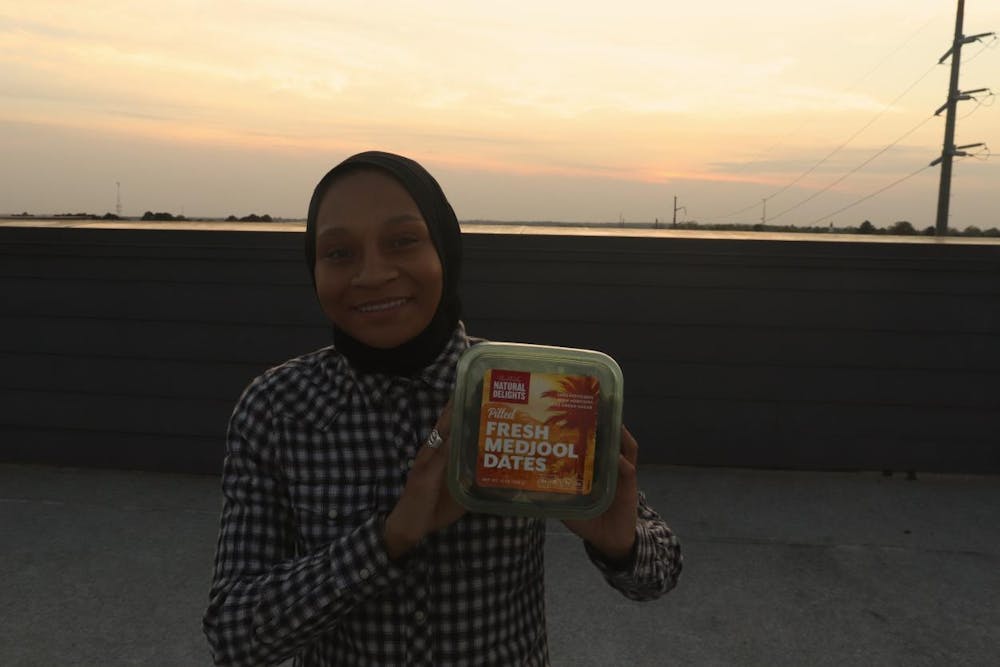 <p>Mikkiya Caldwell holds a box of palm dates at sunset. </p>