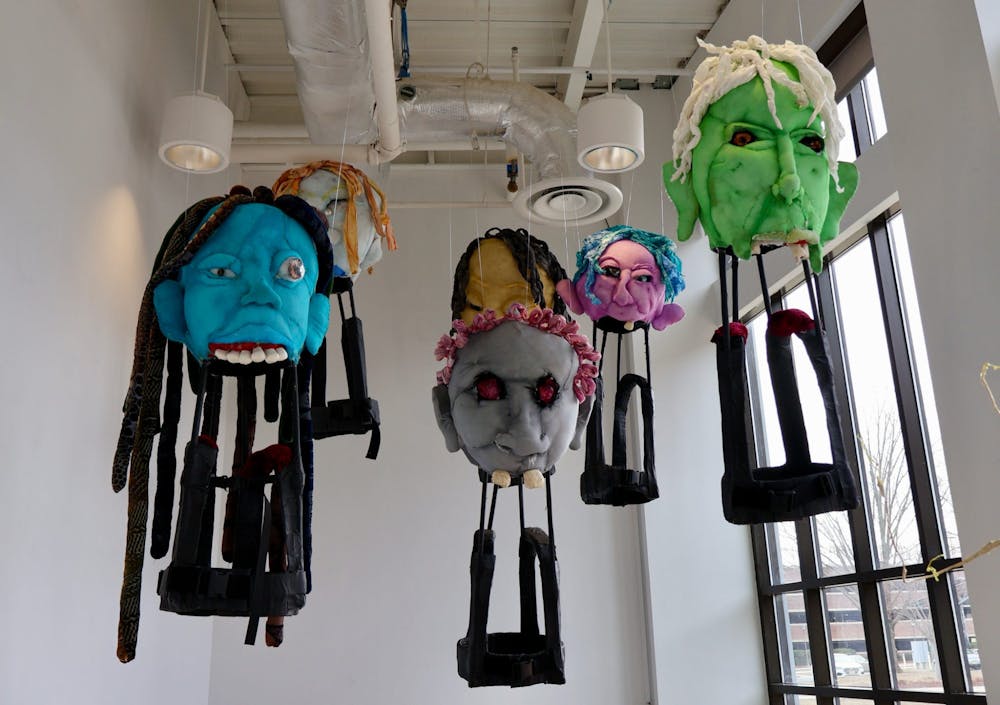 <p><em>Titled “The Giants and Sophie,” viewers are met with six giant heads that tower over observers. (Photo by Erin Reilly / Staff Photographer)</em></p>