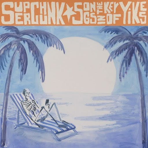 A skeleton sits on the beach staring at a phone in the art for Superchunk’s new record. (Photo courtesy of Apple Music)