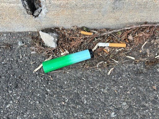 An electronic cigarette and cigarette butts littered on the side of the road. (Photo by Raeanne Raccagno) 