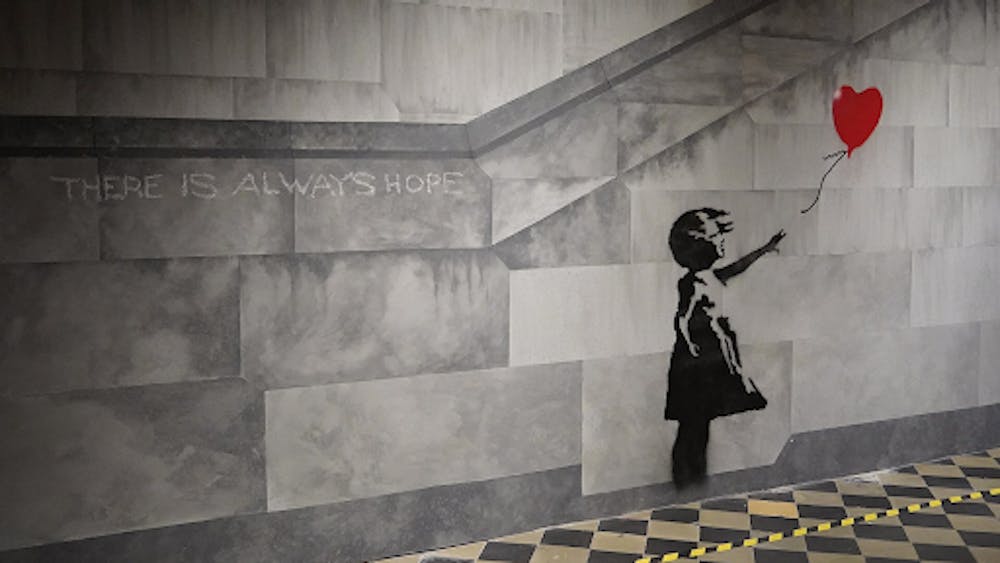 <p><em>Banksy’s “Balloon Girl” piece provides messages of hope and optimism. (Photo courtesy of </em><a href="https://commons.wikimedia.org/wiki/Category:Balloon_Girl_by_Banksy#/media/File:The_World_of_Banksy_2022,_Brussels_(cropped).jpg" target=""><em>Wikimedia Commons</em></a><em>)</em></p>