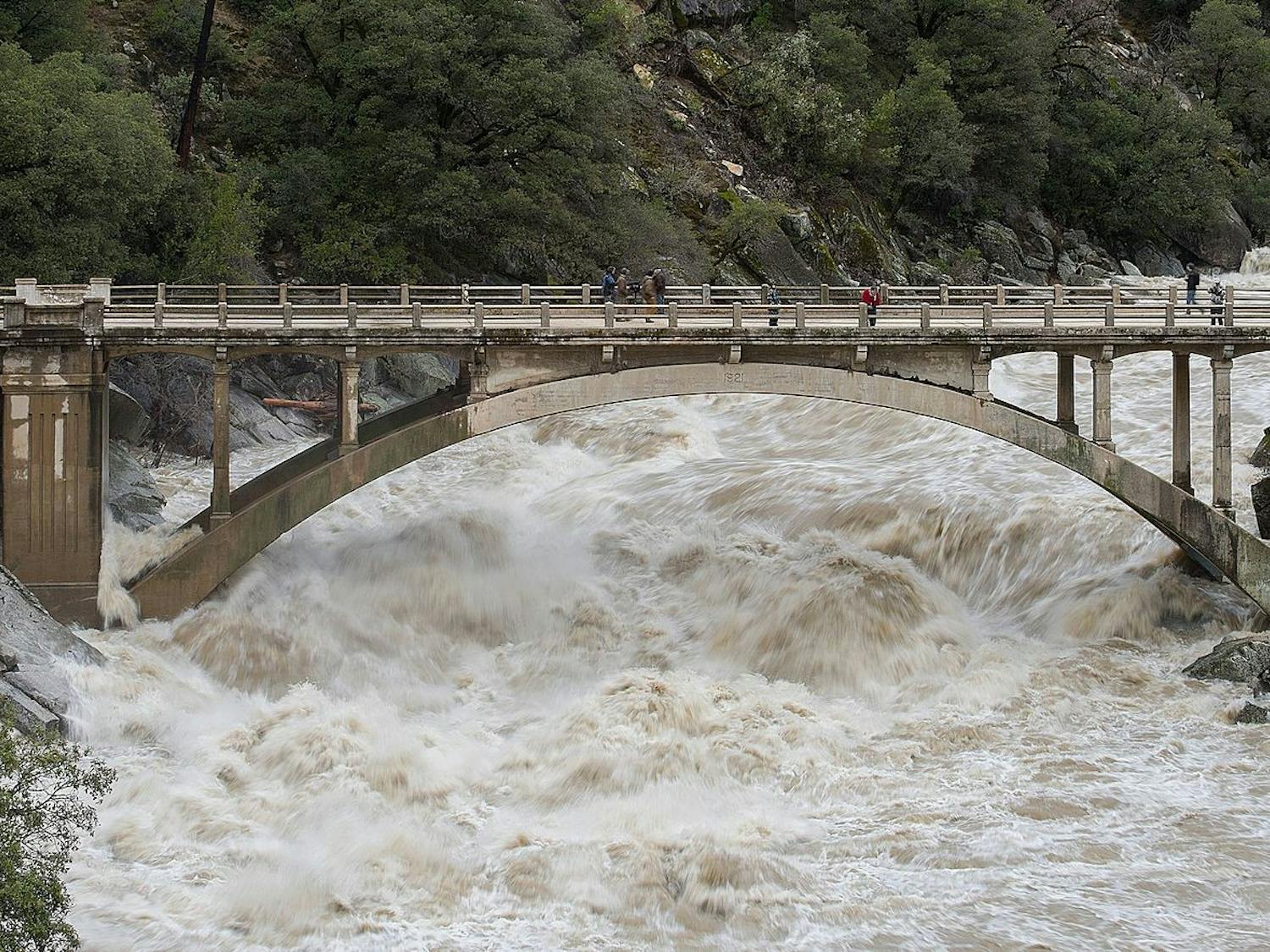 Just one month into the new year, people are already experiencing intense flooding and destruction across California as homes and schools are left as debris (Photo courtesy of Wikimedia Commons / “Flood under the Old Route 49 bridge crossing over the South Yuba River in Nevada City, California” by Kelly M. Grow/ California Department of Water Resources. PD California. January 9, 2017). 
