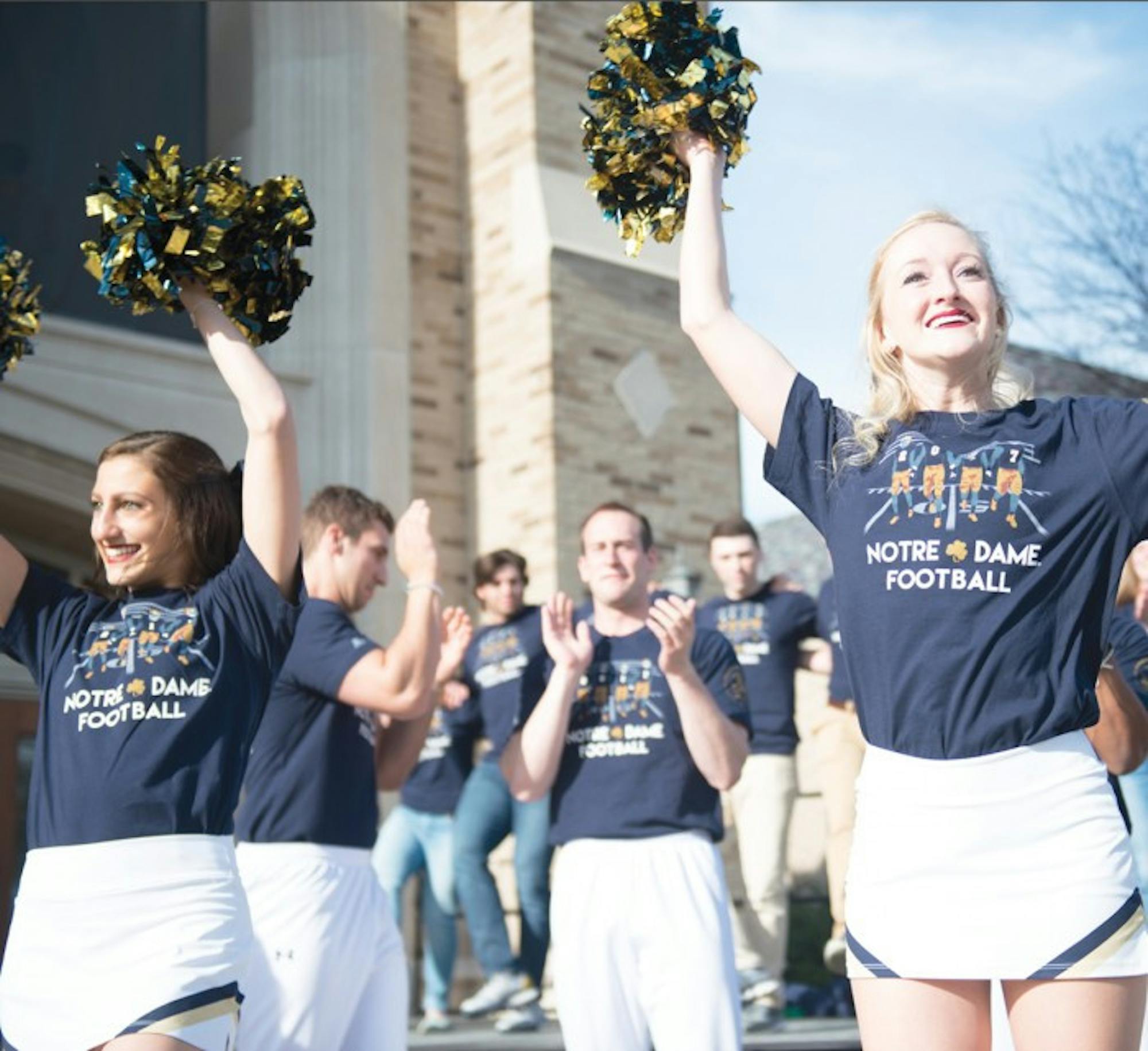 Members of the Notre Dame cheerleading team don the 2017 edition of the shirt as they cheer at the unveiling ceremony at the Hammes Bookstore on Friday.