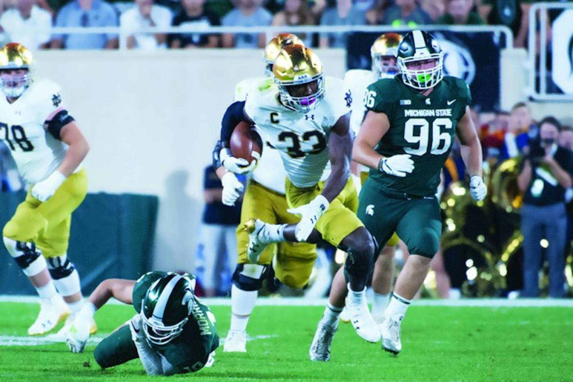 Irish junior running back Josh Adams dodges a Spartan defender during Notre Dame’s 38-18 victory over Michigan State this past Saturday at Spartan Stadium in East Lansing, Michigan. Adams rushed for 57 yards in the game before leaving the game due to ankle stiffness.