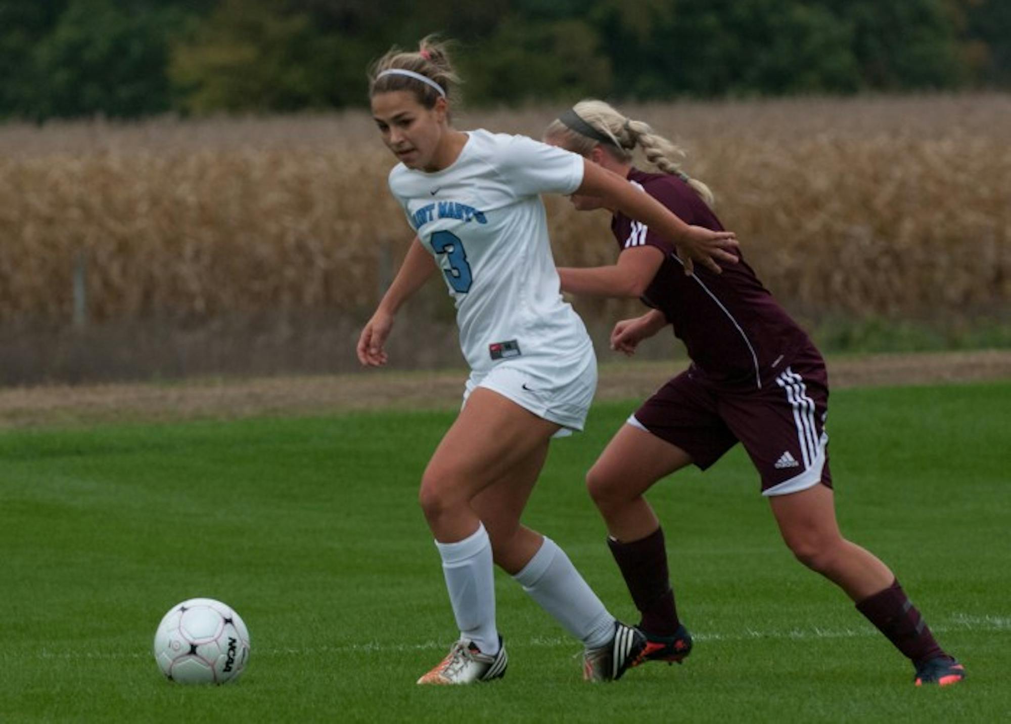 Saint Mary’s junior defender Lindsay Rzepecki shields the ball from an Alma defender during the Belles’ 1-0 loss on Oct. 16, 2013.