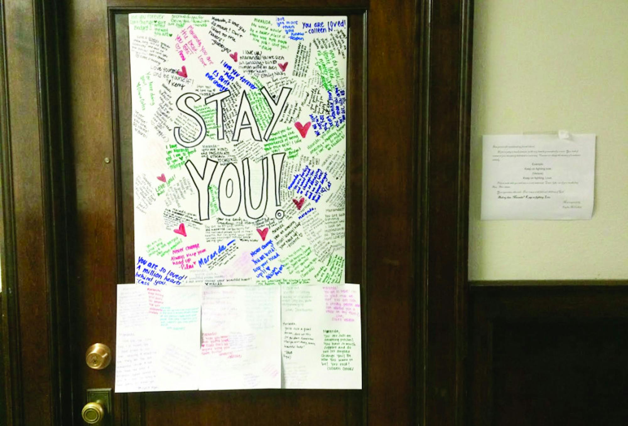 College students write messages of support combatting a hateful message written on Maranda Pennington's white board.