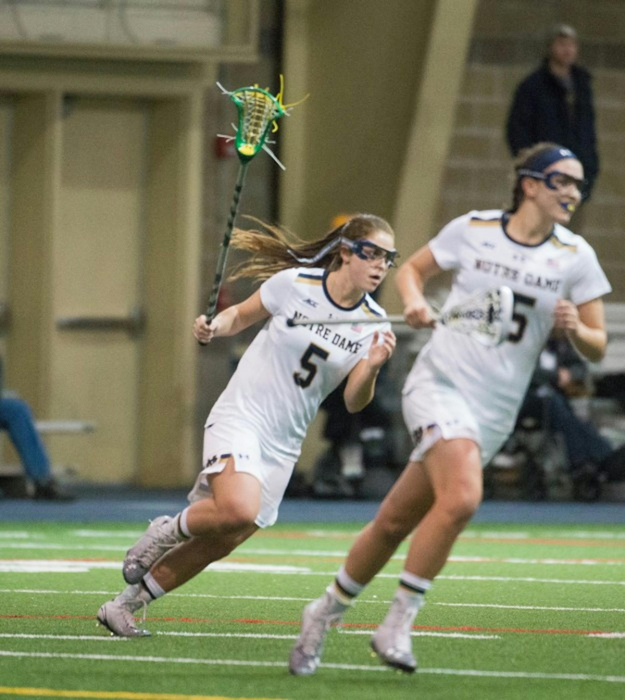 Irish attackers junior Rachel Sexton, left, and sophomore Cortney Fortunato sprint downfield Feb. 15 during a win over Detroit. Both players tallied five goals yesterday in an 18-8 victory over Marquette.