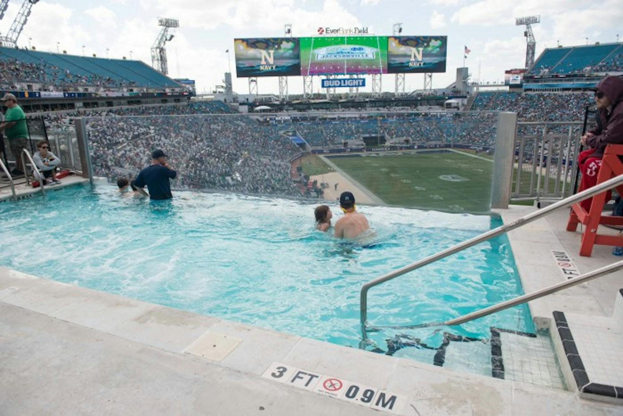 Fans overlook Everbank Field in pool inside stadium. A plexiglass side allows for watching the game even while underwater.