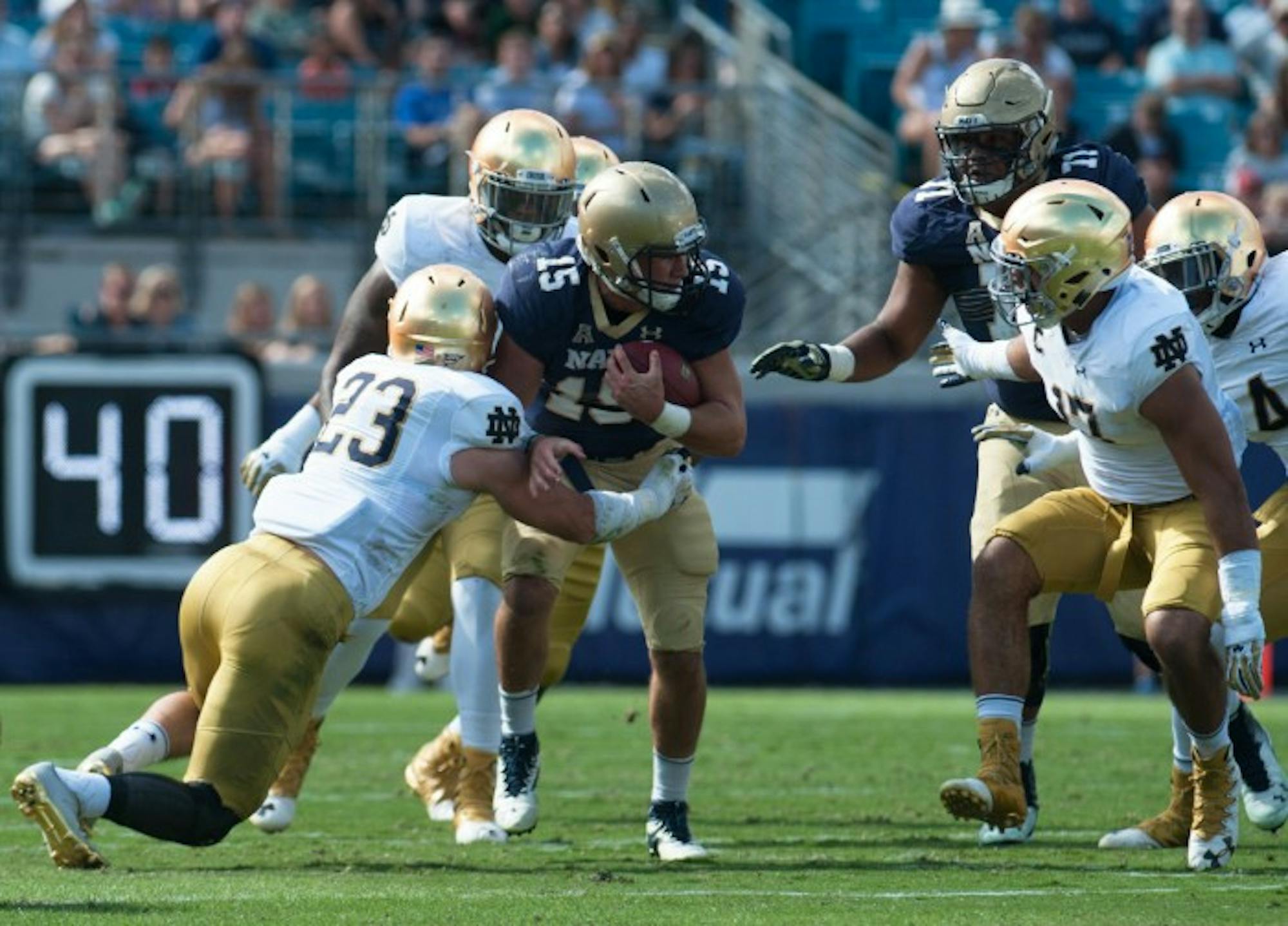 Notre Dame defenders tackle Navy quarterback Will Worth in Saturday's 28-27 loss to the Midshipmen in Jacksonville.