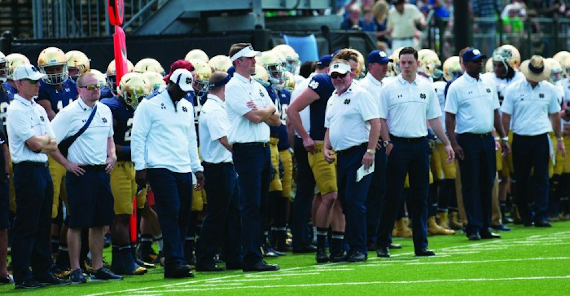 Members of the Irish coaching staff stand on the sidelines during the Blue-Gold Game on April 18. Notre Dame’s new position coaches have found success in their first year despite injuries to starters.