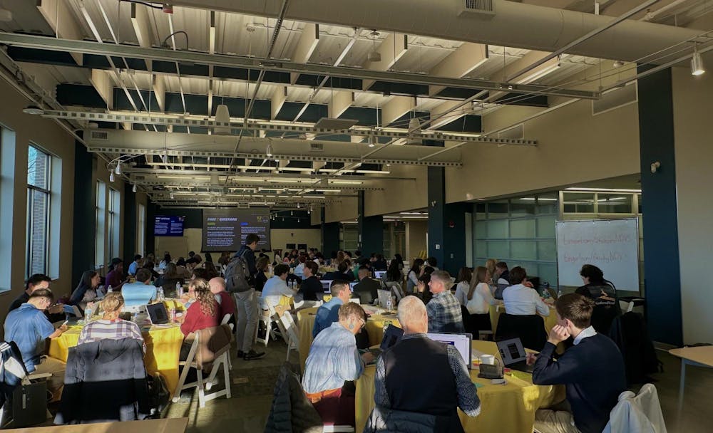 Students and faculty sit in various tables for summit on AI