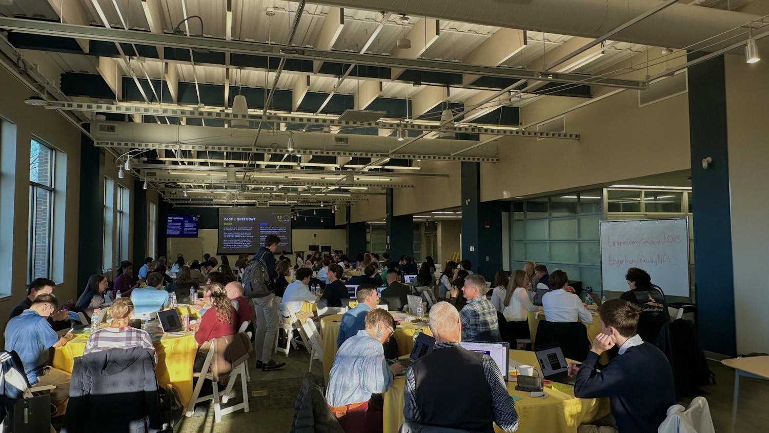 Students and faculty sit in various tables for summit on AI