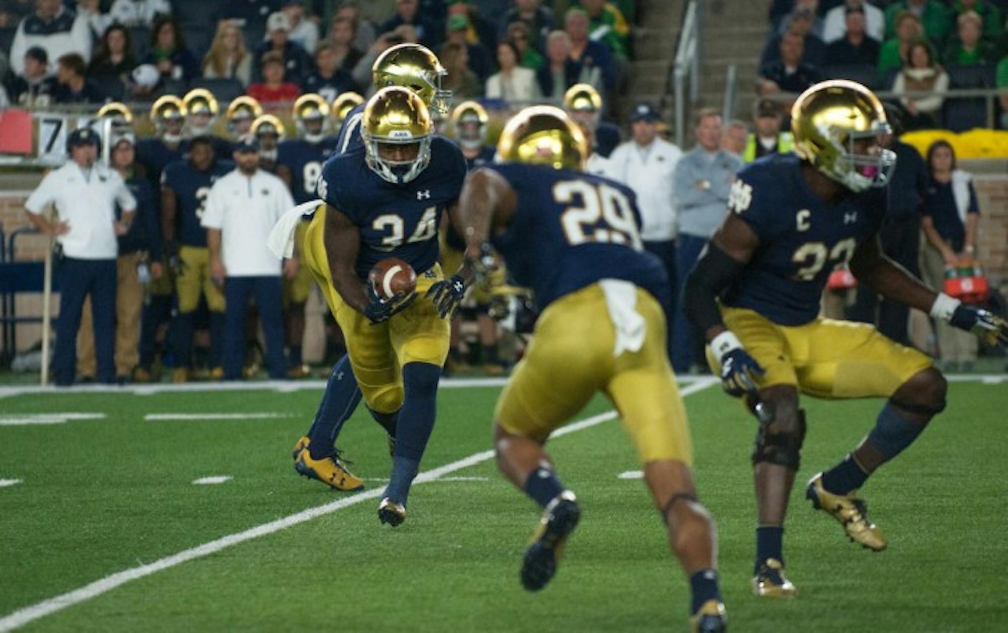 Irish sophomore running back Tony Jones Jr., left, takes a handoff and prepares to give it to sophomore wide receiver Kevin Stepherson, center, on the reverse during Notre Dame's 49-14 win over USC on Saturday at Notre Dame Stadium.