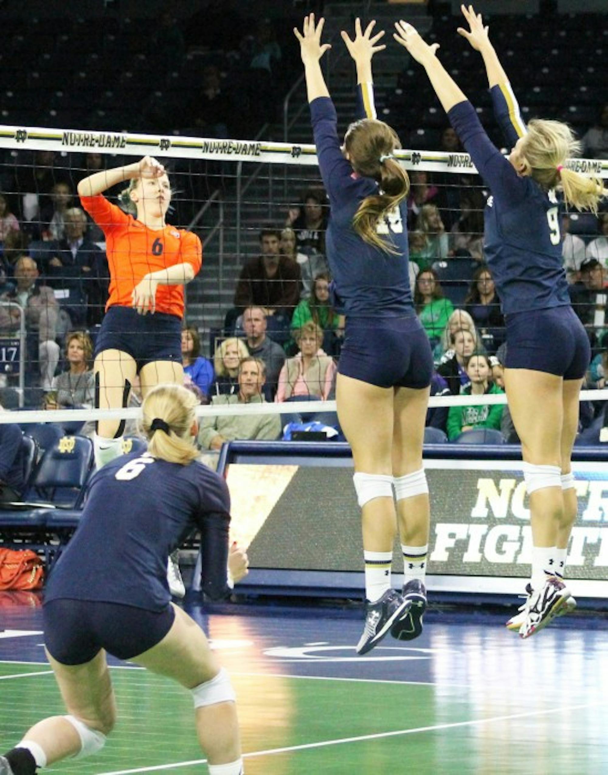 Irish middle blockers junior Katie Higgins, middle, and freshman Rebecca Nunge, right, attempt to block the ball during Notre Dame’s 3-2 loss to Syracuse on Oct. 4 at Purcell Pavilion.