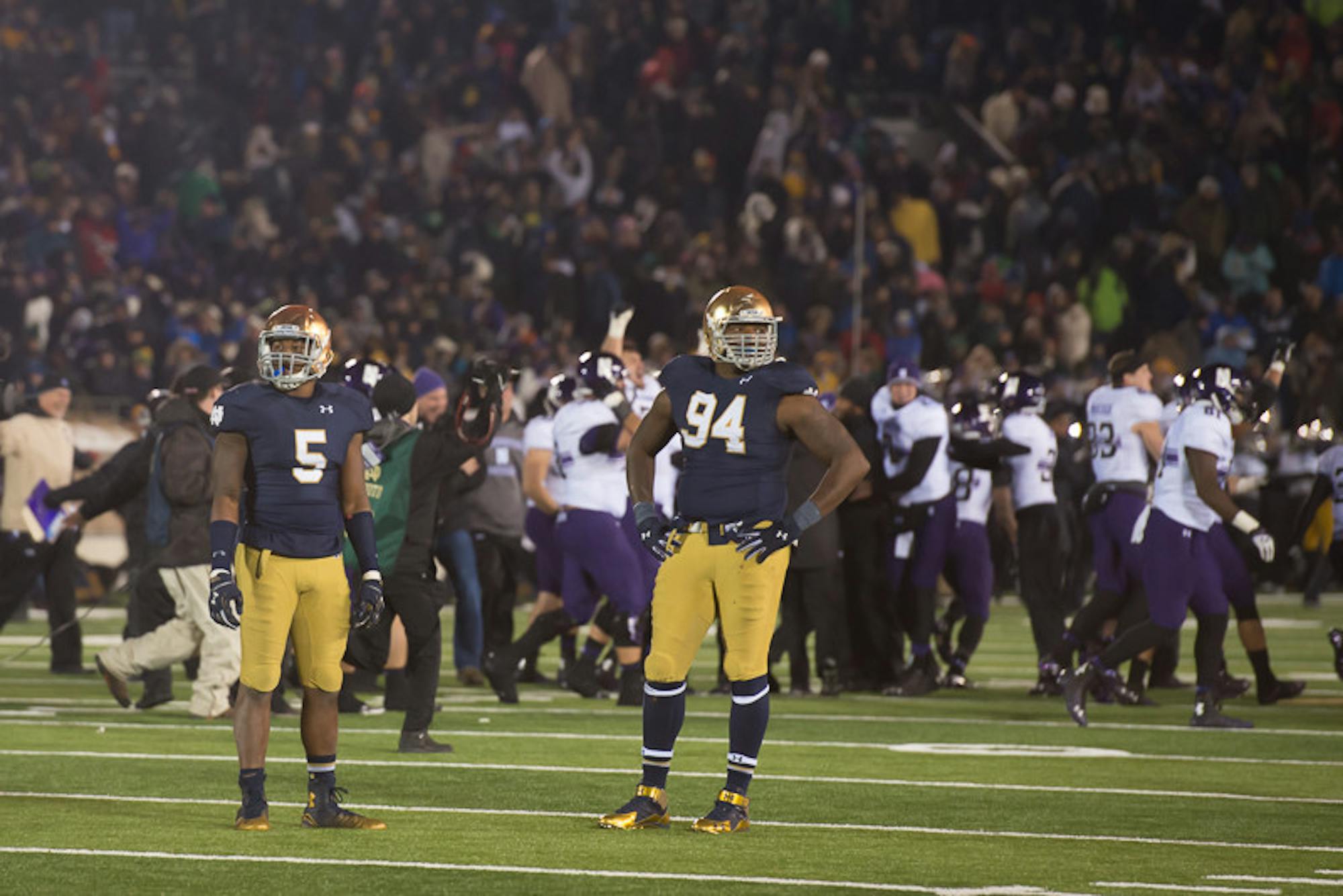 Irish freshman linebacker Nyles Morgan, left, and junior defensive lineman Jarron Jones stand on the field while Northwestern celebrates its 43-40 overtime victory over Notre Dame on Saturday at Notre Dame Stadium.