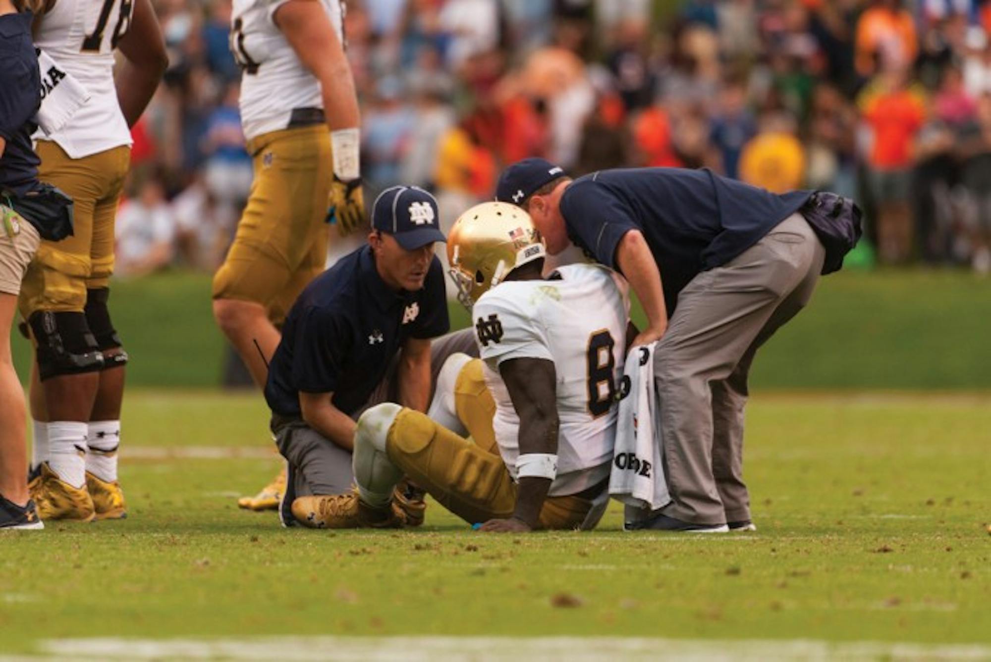 Irish junior quarterback Malik Zaire is surrounded by trainers after fracturing his ankle during Notre Dame’s 34-27 win over Virginia on Saturday at Scott Stadium. Zaire threw for 115 yards and a touchdown in Charlottesville, Virginia, before going down with the season-ending injury near the end of the third quarter.