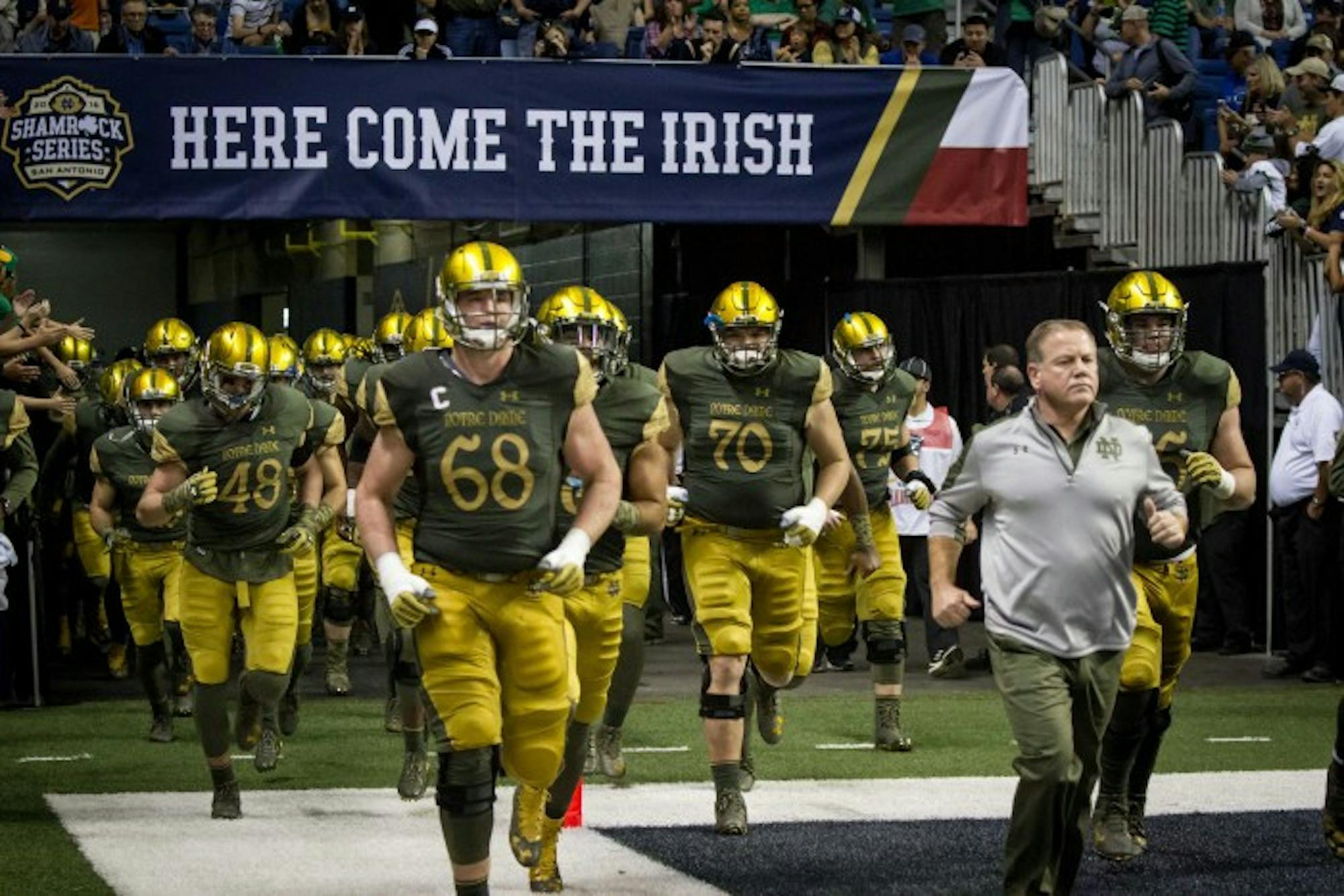 Notre Dame players and head coach Brian Kelly, right, run onto the field before Notre Dame’s 44-6 win over Army on Saturday at the Alamodome.