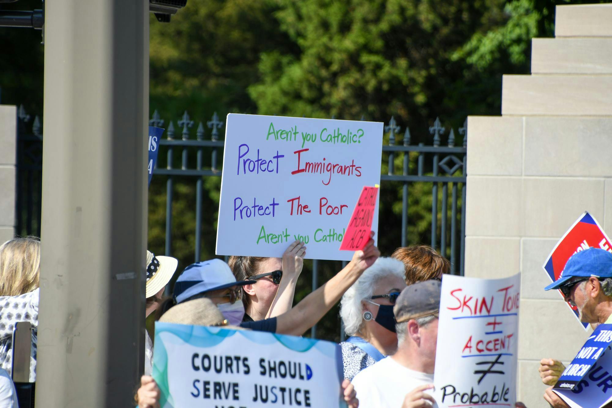 Protesters gather with signs against the presence of Amy Coney Barrett