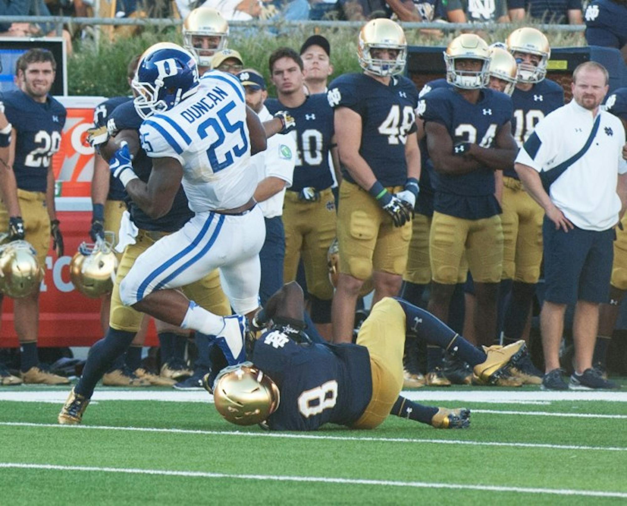 Irish sixth-year graduate student Avery Sebastian, on the ground, helps tackle a Duke player during Notre Dame’s loss Sept. 24.