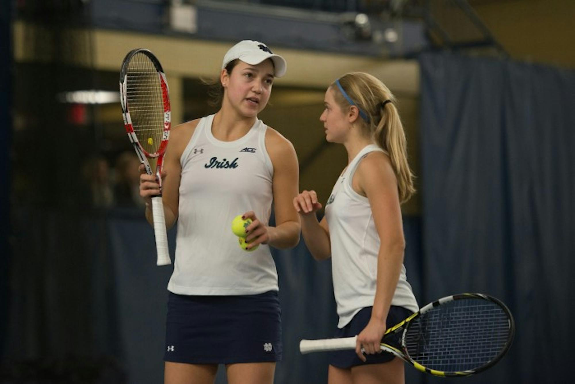 Notre Dame’s top doubles duo of junior Quinn Gleason, left, and sophomore Monica Robinson talk strategy during Notre Dame’s 6-1 loss to Stanford on Friday at Eck Tennis Center.