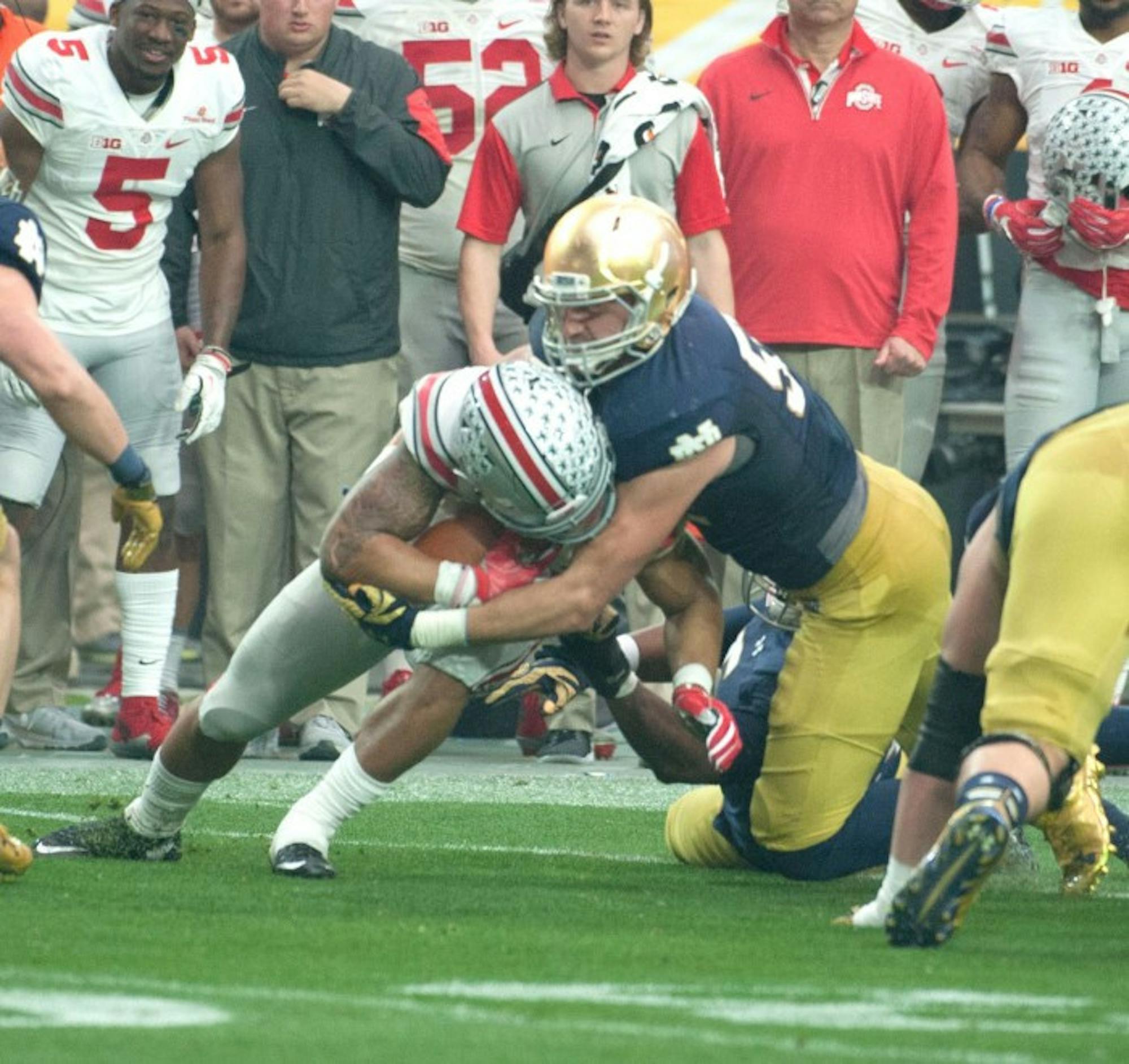 Irish graduate student linebacker Jarrett Grace wraps up Buckeyes junior running back Ezekiel Elliott during Notre Dame's loss to Ohio State on Friday. Grace entered the game after junior Jaylon Smith and freshman Te'von Coney both suffered injuries and finished with nine tackles.