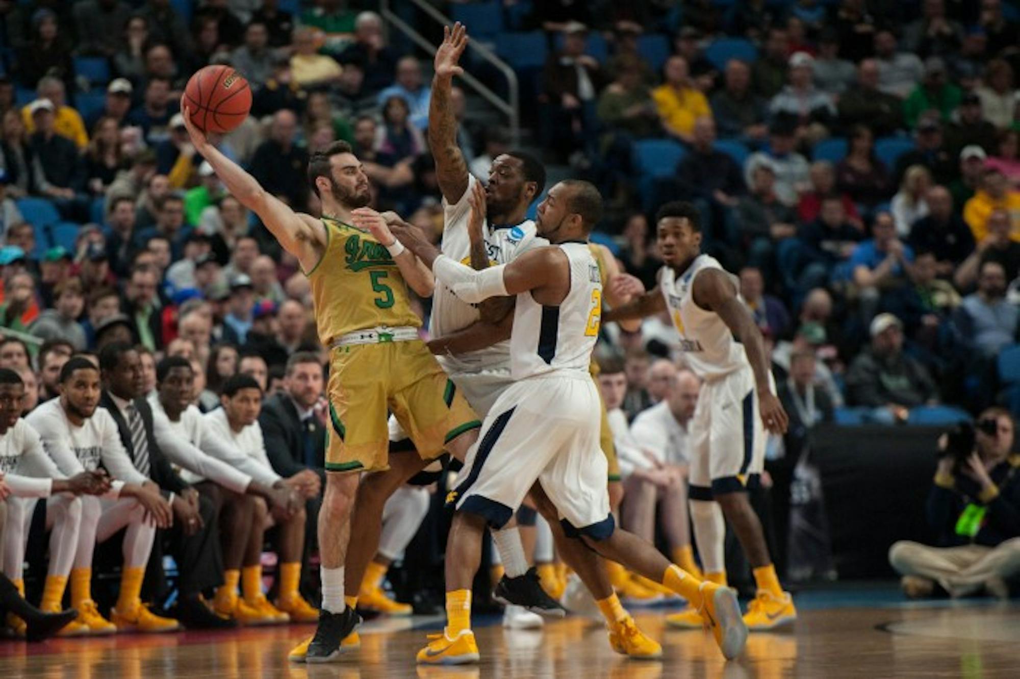 Irish junior guard Matt Farrell fends off two defenders during Notre Dame's 83-71 loss to West Virginia on Saturday at KeyBank Arena.
