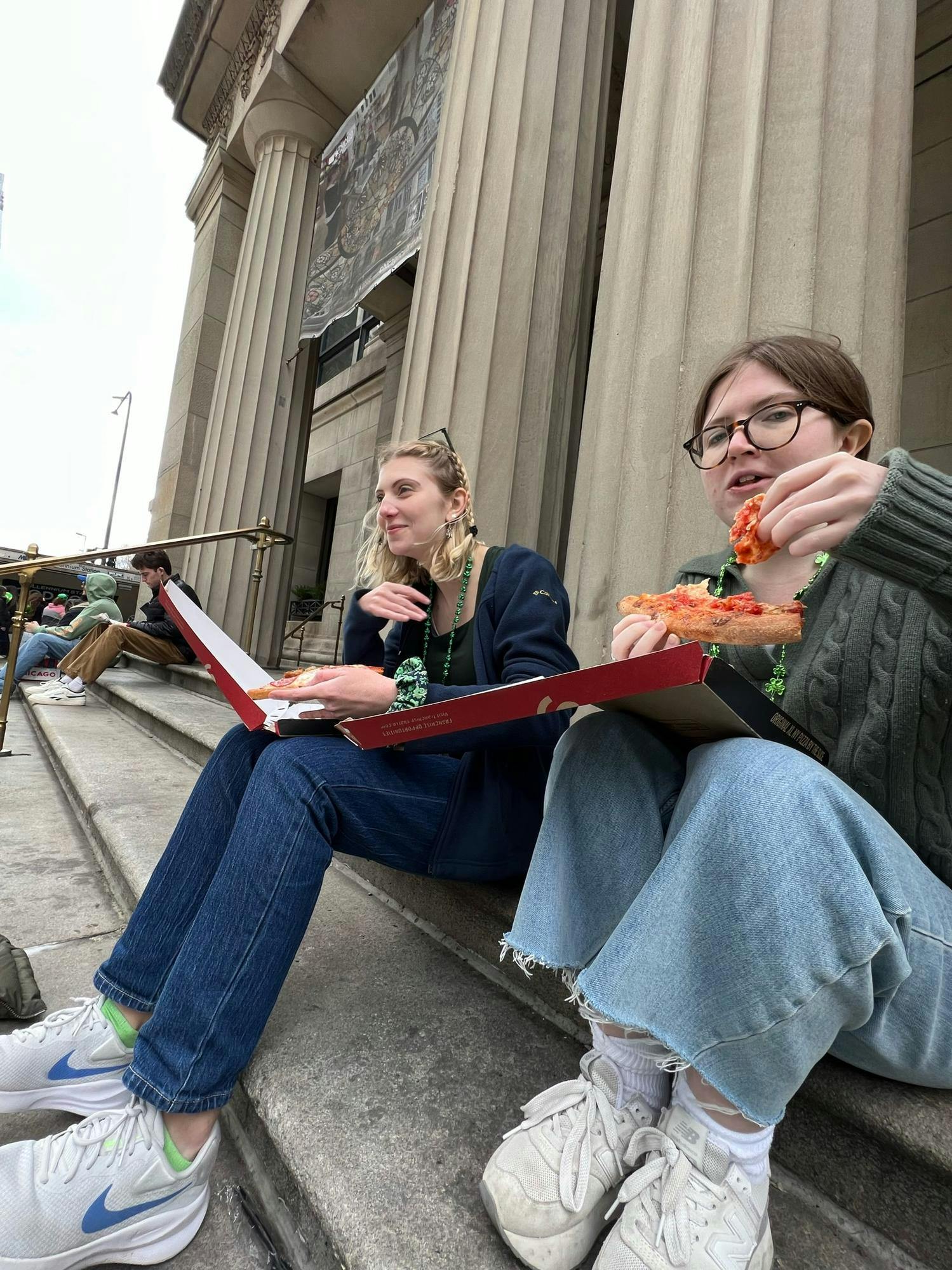 The author and friend eat pizza on the steps outside of Millenium Station, in a moment of low morale, just before a gust of wind blows away their boxes.