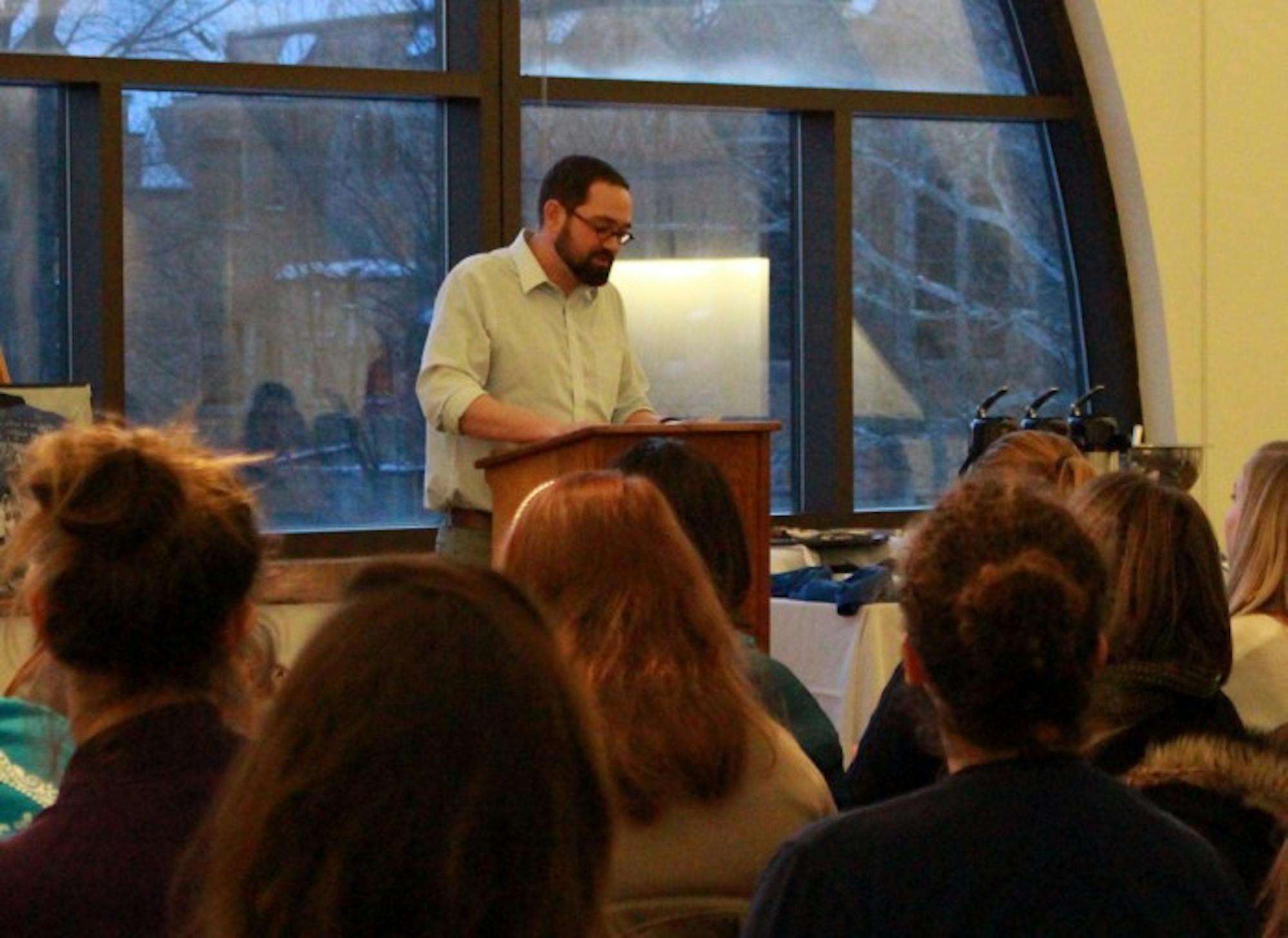 Aaron Bremyer, head of the English writing center at Saint Mary’s, reads a poem by a student during the “Then and Now” poetry reading.