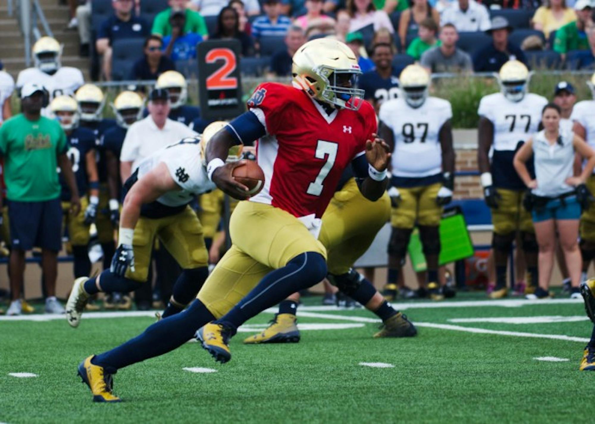 Irish junior quarterback Brandon Wimbush tucks the ball and scrambles from the pocket during Notre Dame’s New and Gold scrimmage Sunday at Notre Dame Stadium.