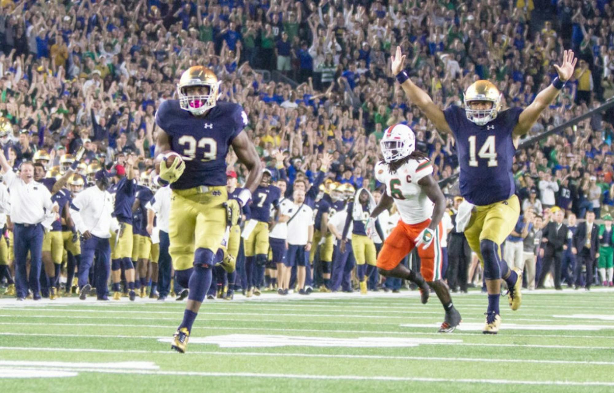 Irish sophomore running back Josh Adams sprints into the end zone to score the game-tying touchdown against Miami on Saturday at Notre Dame Stadium as junior quarterback DeShone Kizer, right, begins celebrating with the rest of the Irish faithful. Sophomore kicker Justin Yoon hit a 27-yard field goal with 30 seconds left to give the Irish the 30-27 win.